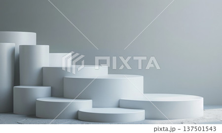 Several white cylindrical podiums of varying heights are neatly arranged in a stepped pattern against a minimalist gray background in a modern studio setting. 137501543
