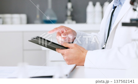 Tablet, hands or scientist with research in laboratory for a chemistry report or scientific test feedback. Medical analysis closeup, man typing or science update for online medicine development news Tablet, hands or scientist with research in laboratory for a chemistry report or scientific test feedback. Medical analysis closeup, man typing or science update for online medicine development news 137502141