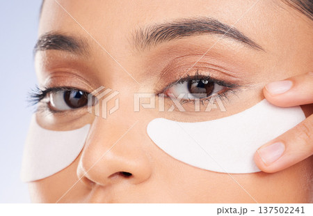 Skincare, pads and eyes, portrait of woman with product on face for anti aging or skin glow on studio background. Cosmetics, facial detox and model with beauty solution or collagen for dermatology. Skincare, pads and eyes, portrait of woman with product on face for anti aging or skin glow on studio background. Cosmetics, facial detox and model with beauty solution or collagen for dermatology. 137502241
