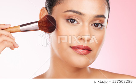Beauty, makeup and portrait of woman in studio with a brush for cheek blush or foundation for glam routine. Cosmetics, face and young female model with cosmetology product isolated by pink background Beauty, makeup and portrait of woman in studio with a brush for cheek blush or foundation for glam routine. Cosmetics, face and young female model with cosmetology product isolated by pink background 137502289
