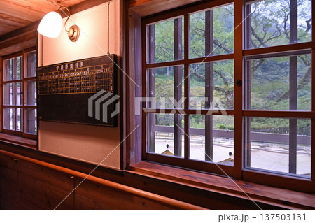 雨の日の窓辺を照らす明かりと壁に掲げられた古い学習時間割表 137503131