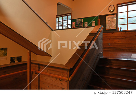 掲示板や時計が当時のまま残る温かい雰囲気の木造校舎の階段踊り場 137503247