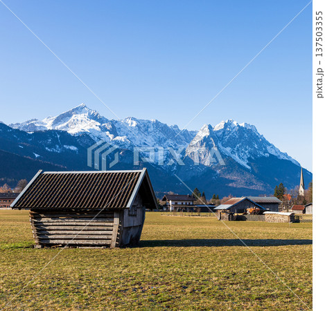 Traditional wooden hut in Bavarian countryside with snow capped Alps mountains and clear blue sky Traditional wooden hut in Bavarian countryside with snow capped Alps mountains and clear blue sky 137503355