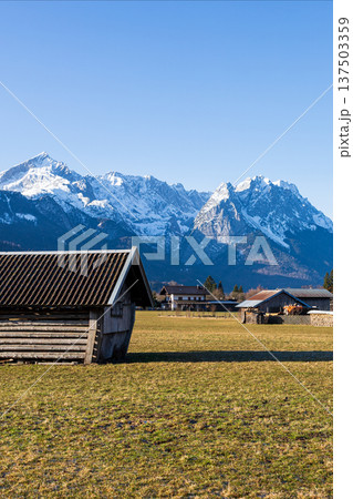 Traditional wooden hut in Bavarian countryside with snow capped Alps mountains and clear blue sky Traditional wooden hut in Bavarian countryside with snow capped Alps mountains and clear blue sky 137503359
