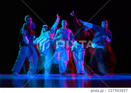 Hip hop dancers performing synchronized street dance with neon lighting and motion blur 137503857