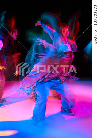 Female street dancer performing hip hop move with neon light trails and motion blur. Female street dancer performing hip hop move with neon light trails and motion blur. 137503873