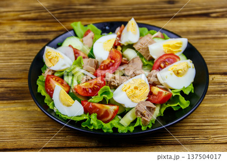 Tasty tuna salad with eggs, lettuce and fresh vegetables on wooden table 137504017