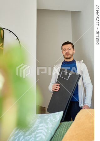 Man carrying exercise mat in living room before home workout 137504457