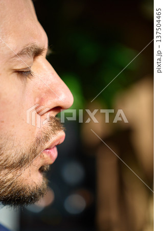 Close-up profile of man exhaling during breathing exercise indoors Close-up profile of man exhaling during breathing exercise indoors 137504465