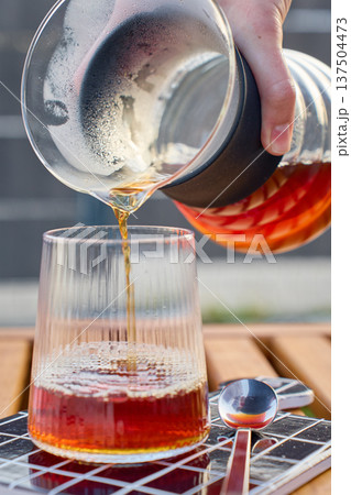 Pour over coffee pouring from glass carafe into ribbed glass outdoors Pour over coffee pouring from glass carafe into ribbed glass outdoors 137504473