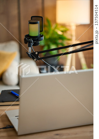 Podcast microphone on boom arm above laptop in home studio workspace Podcast microphone on boom arm above laptop in home studio workspace 137504514