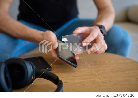 Man applying protective glass screen protector to smartphone at home 137504520