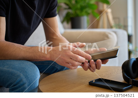 Man applying protective glass screen protector to smartphone at home 137504521