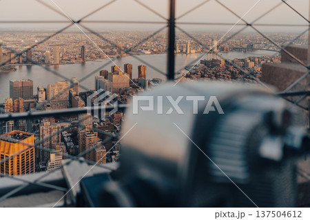 Visitors observe New York City skyline through a telescope at sunset 137504612