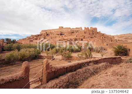 Moroccan kasbah Ait Ben Haddou with palm trees and tourists exploring Moroccan kasbah Ait Ben Haddou with palm trees and tourists exploring 137504642