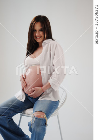 Expecting mother relaxing in a studio setting Expecting mother relaxing in a studio setting 137506271