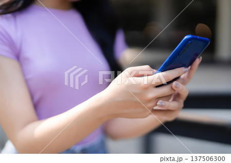 Asian adult female hands using smartphone outdoor interacting digital content mobile communication technology modern lifestyle connecting digital world everyday activity 137506300