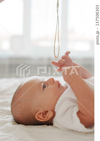 Baby gazing at a necklace dangling above Baby gazing at a necklace dangling above 137506303