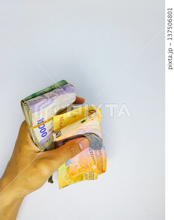 Hand holding banknotes indonesian rupiah of different denominations isolated on a white background Hand holding banknotes indonesian rupiah of different denominations isolated on a white background 137506801