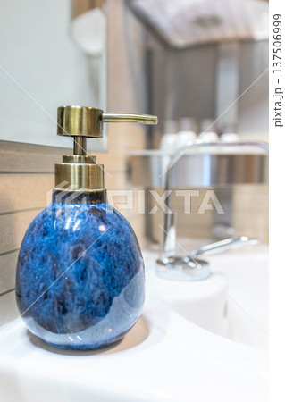 Blue ceramic soap dispenser on white sink 137506999