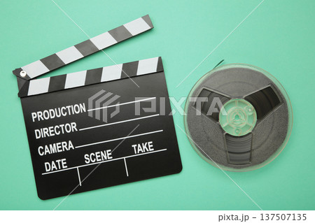 Movie clapper with popcorn and film reels on mint background 137507135