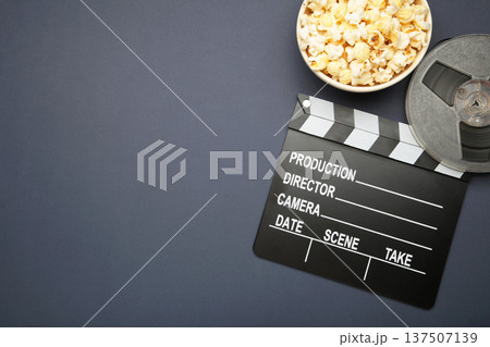 Movie clapper with popcorn and film reels on dark blue background 137507139