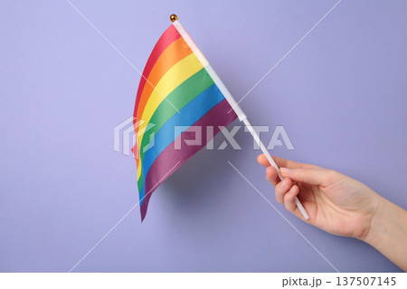 Hand holding rainbow flag on purple background. Hand holding rainbow flag on purple background. 137507145