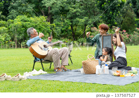 The senior man help to take the photo of young people family man, woman and child during holiday at public park. The senior man help to take the photo of young people family man, woman and child during holiday at public park. 137507527