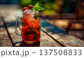 Fresh strawberry mojito with mint leaves and crushed ice in mason jar glass, strawberry mojito glowing red under sunlight on wooden table, tropical cocktail summer refreshment mood 137508833