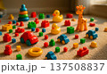Plastic toy cars and yellow ducks scattered on soft carpet with colorful blocks and stacking rings; cars dominate bright playtime setup filled with cheerful toddler toys 137508837