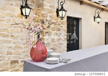 Long outdoor buffet table against stone wall with pink blossoms at a wedding Long outdoor buffet table against stone wall with pink blossoms at a wedding 137509831