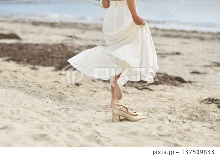 Bride in white dress and golden shoes on the beach Bride in white dress and golden shoes on the beach 137509833
