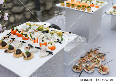 Gourmet wedding canapes displayed on elevated white trays outdoors reception 137509836