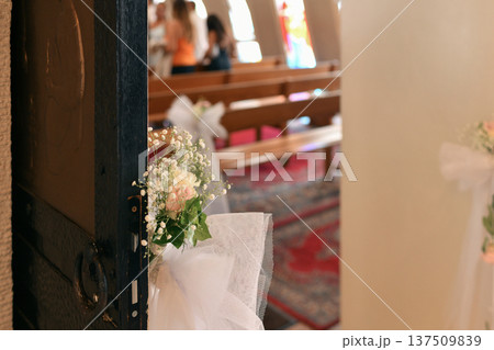Flower adorned church pews viewed through open rustic wooden doorway Flower adorned church pews viewed through open rustic wooden doorway 137509839
