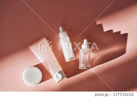 Skincare cosmetic products on pink background casting shadows 137510228