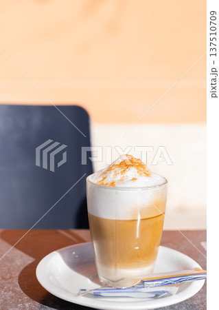 Cup of cappuccino stands on a table in a cafe outside. Cup of cappuccino stands on a table in a cafe outside. 137510709