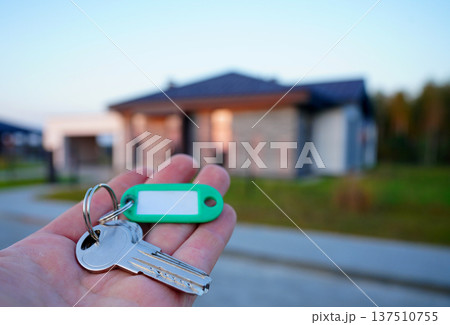 Buying home. Hand holding a bunch of keys at modern private home. Concept of buying real estate 137510755