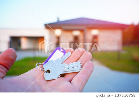 Buying home. Hand holding a bunch of keys at modern private home. Concept of buying real estate Buying home. Hand holding a bunch of keys at modern private home. Concept of buying real estate 137510759