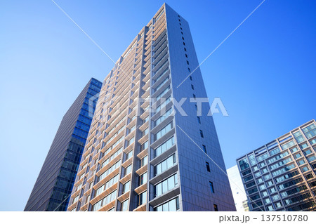 Glass tower building on blue sky background. Facade of new modern business office building. Glass tower building on blue sky background. Facade of new modern business office building. 137510780