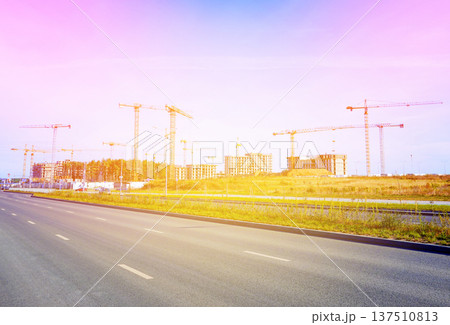 Empty road during sunlight near construction site with cranes in city area. Renovation, building Empty road during sunlight near construction site with cranes in city area. Renovation, building 137510813