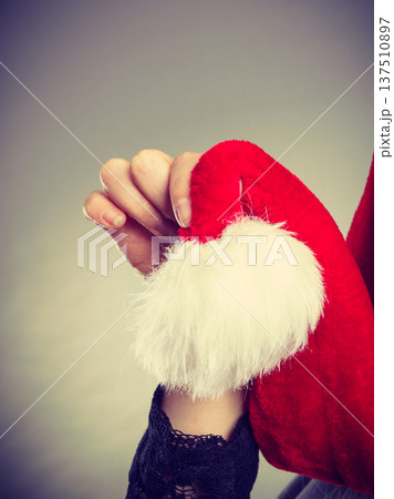 Woman holding white pompon on Santa hat Woman holding white pompon on Santa hat 137510897