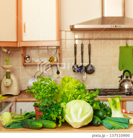 Many green vegetables on kitchen table 137510900