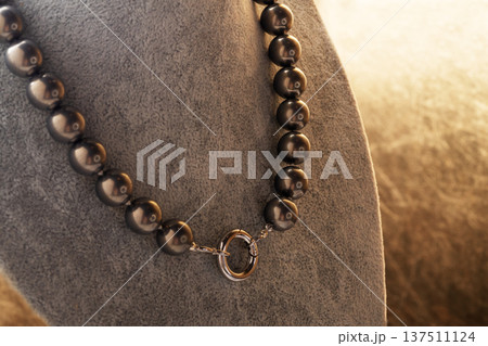 author beautiful  steel color pearls necklaces with heart pendant demonstrated on maneken. fashion and jewelry concept 137511124