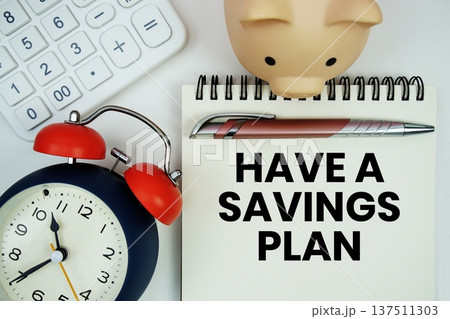 Have A Savings Plan text written notepad with calculator, piggy bank and alarm clock on white background 137511303