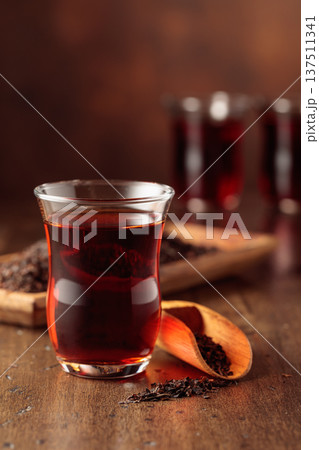 Glass transparent cup of black tea and dry tea on a wooden table. 137511341