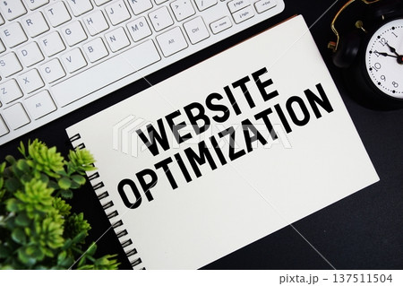 Website Optimization text written on notepad with keyboard and alarm clock on black background 137511504