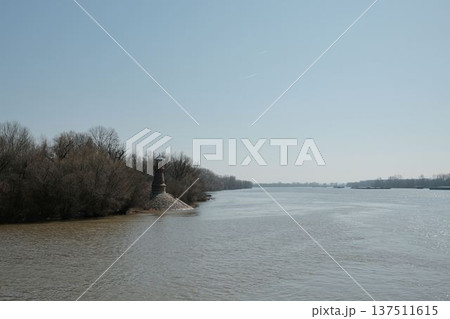 Historic river lighthouse standing at the riverbank near Pancevo on the Danube river in Serbia. Calm water landscape with navigation tower used as a landmark for river transport and shipping Historic river lighthouse standing at the riverbank near Pancevo on the Danube river in Serbia. Calm water landscape with navigation tower used as a landmark for river transport and shipping 137511615