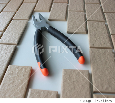 Rubberized Handles Of Pliers On Free Space On A Surface Covered With Brick Tiles. Home Repairing Square Stock Photo Rubberized Handles Of Pliers On Free Space On A Surface Covered With Brick Tiles. Home Repairing Square Stock Photo 137511629