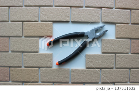 Opened jaws pliers on clean place of a missing tiles on a fully tiled surface Opened jaws pliers on clean place of a missing tiles on a fully tiled surface 137511632