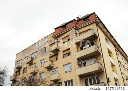 Aged residential apartment building with peeling facade and balconies in Sombor, Serbia. Urban housing, renovation and real estate concept in Eastern Europe Aged residential apartment building with peeling facade and balconies in Sombor, Serbia. Urban housing, renovation and real estate concept in Eastern Europe 137511768